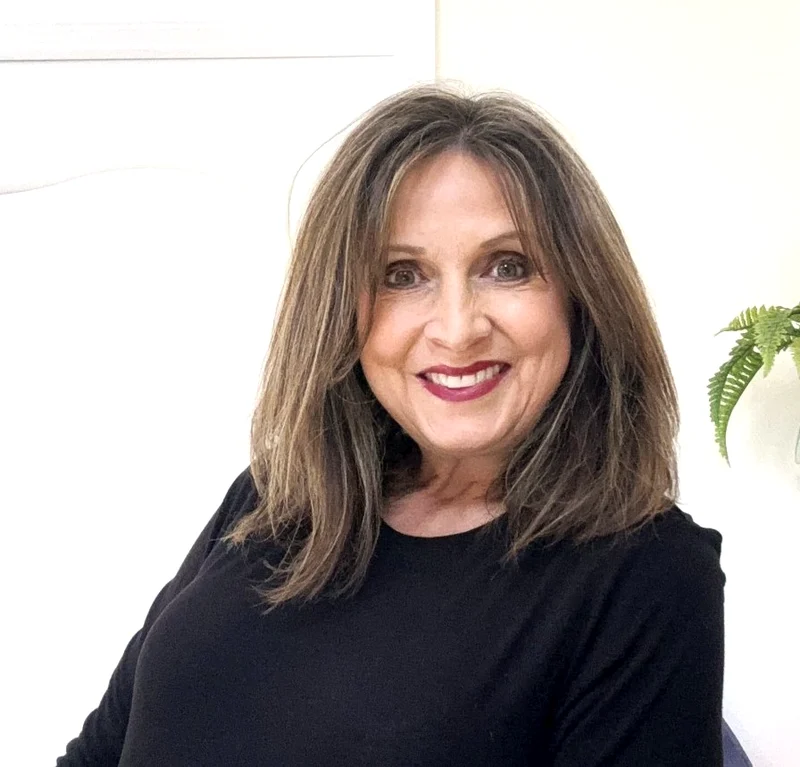 Paula Fehringer, esthetician, in a bright studio setting with a warm smile